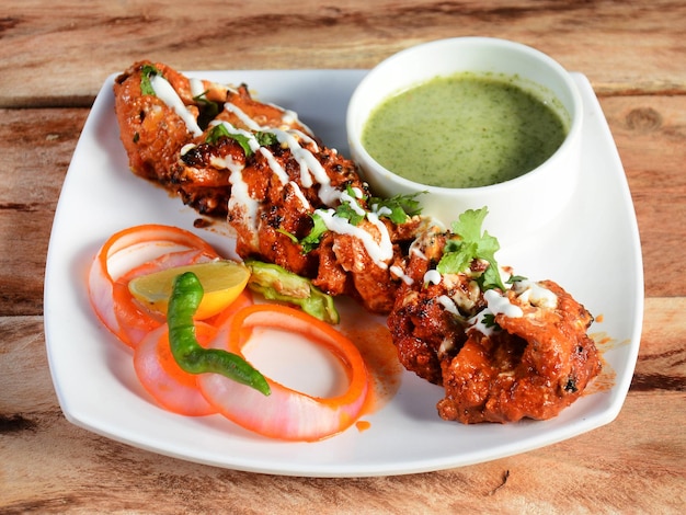 Achari Paneer tikka is een heerlijke starter gemaakt met Indiase kwark gemarineerd in een achari augurk kruiden marinade geserveerd op een rustieke houten achtergrond selectieve focus