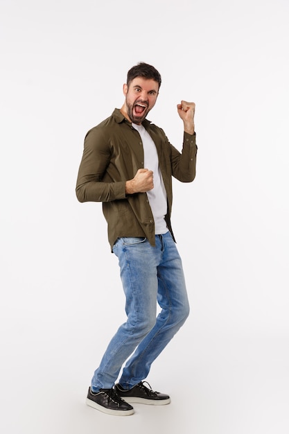 Achievement, goal and win concept. Full-length vertical shot cheerful handsome successful businessman in casual outfit, dancing triumphing and celebrating victory, become champion, fist pump