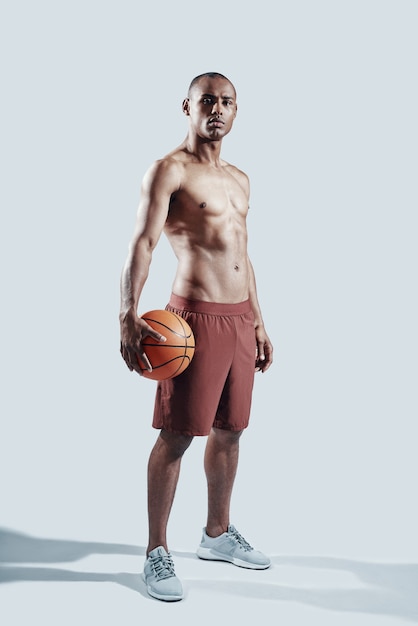 Achieving best results. Full length of handsome young African man in sports clothing looking at camera while standing against grey background