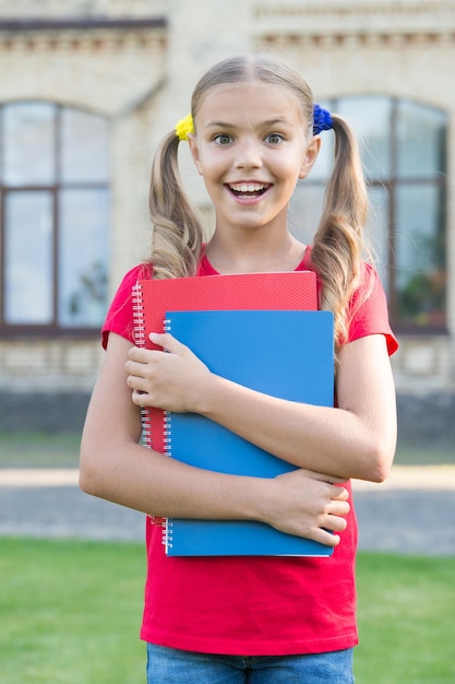 Achieving high standards Cute little bookworm Cute smiling small child hold books educational institution background Little girl school student Secondary school student School education concept