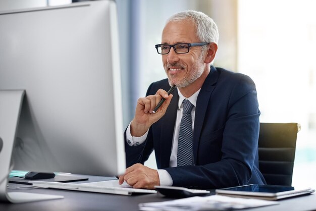 Achieving success the old fashioned way through hard work Shot of a smiling mature businessman working at his desk in an office