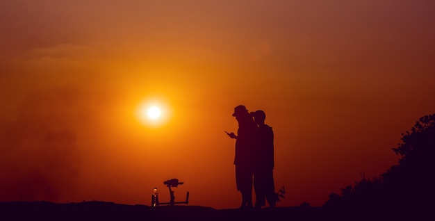 Achter de schermen. Het team filmde de filmscène buiten bij zonsondergang. Concept silhouet. Werk van de videograaf. Het filmen van de MV.