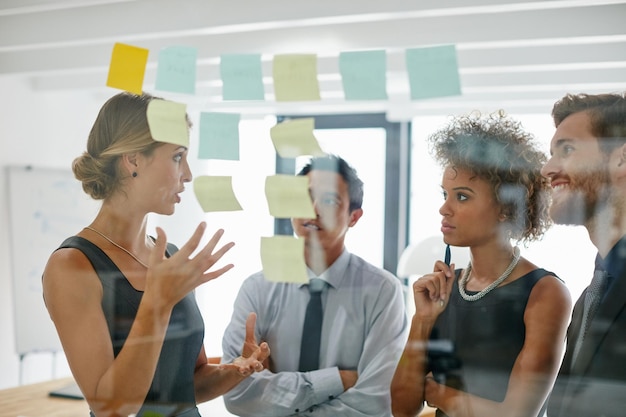 Foto achter elk geweldig idee zit een geweldig verhaal shot van collega's die tijdens een brainstormsessie plaknotities tegen de muur gebruiken