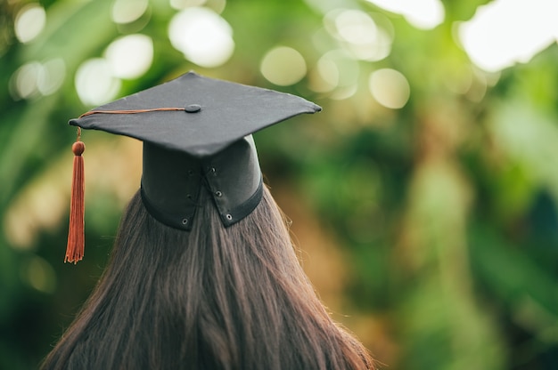 Achter foto van universitair afgestudeerde draagt toga en zwarte pet bruine kwast