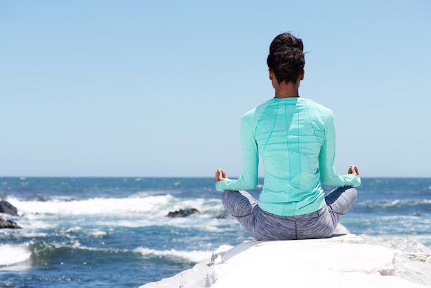 Achter van yoga vrouw op het strand