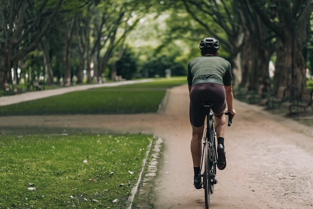 Achteraanzicht actieve jonge man fietsten in het groene stadspark