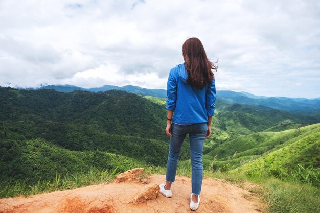 Achteraanzicht beeld van vrouwelijke reiziger kijken naar een prachtig uitzicht op de groene bergen