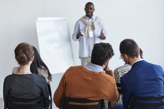 Achteraanzicht bij mensen die in het publiek zitten op een zakelijke conferentie of een onderwijsseminar en luisteren naar de coach, kopieer ruimte