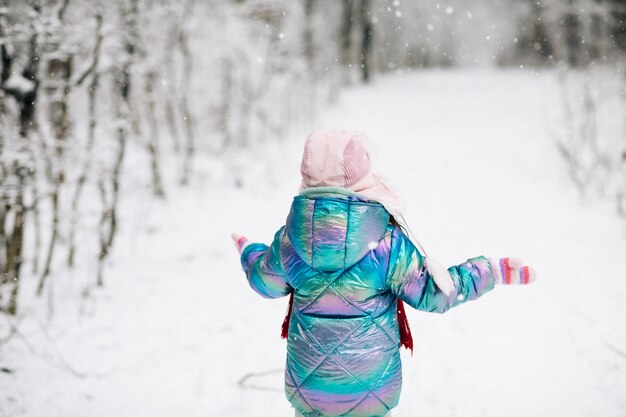 Achteraanzicht gelukkig lachend kind, schattig meisje in een kleurrijke kleding en hoed