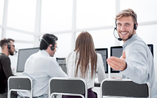 Achteraanzicht jonge klantenservicemedewerker die aan zijn bureau zit