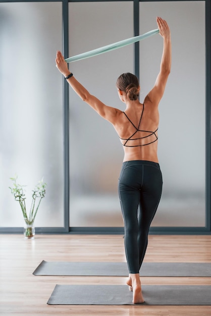 Achteraanzicht Jonge vrouw in sportieve kleding en met een slank lichaam heeft een fitness-yogadag binnenshuis