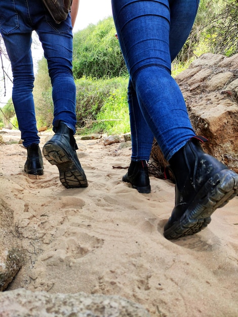 Achteraanzicht lage sectie van paar in spijkerbroek lopen op onverharde weg focus op wandelschoenen