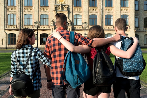 Achteraanzicht medium shot van knuffelen tieners gaan naar de middelbare school