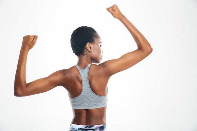 Achteraanzicht portret van Afro-Amerikaanse vrouw die haar biceps toont geïsoleerd op een background