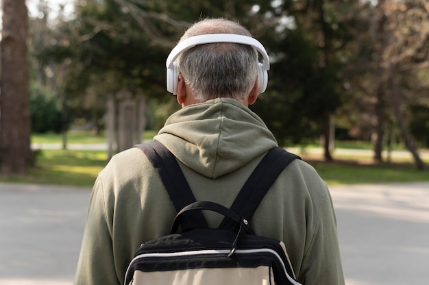 Foto achteraanzicht senior man luisteren naar muziek in een headset