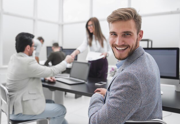 Achteraanzicht succesvolle zakenman die aan zijn bureau zit en naar de camera kijkt