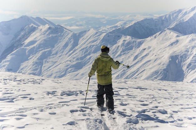 Achteraanzicht van actieve skiër in felgele sportkleding rijden de bergen af