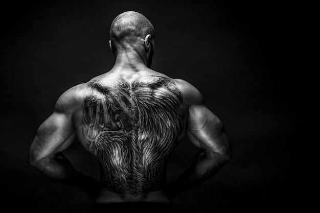Achteraanzicht van bodybuilder met tattoed met uitgestrekte armen