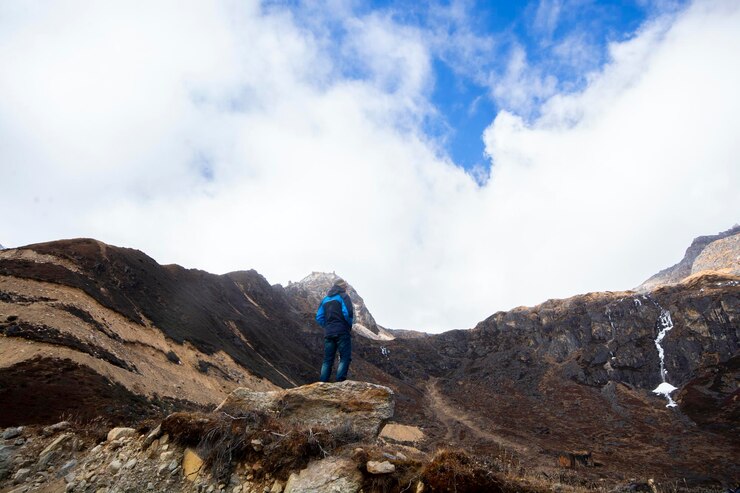 Foto achteraanzicht van de man die op de berg staat tegen de bewolkte hemel