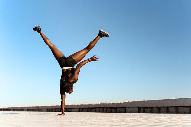 Achteraanzicht van de vrouw die yoga doet en op haar handen bij de zee staat