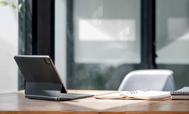 Achteraanzicht van draagbare tablet met toetsenbord en document op houten tafel in moderne kantoorruimte.