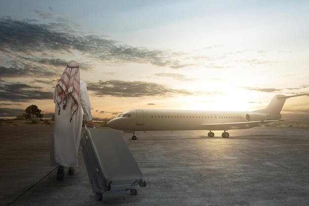 Achteraanzicht van een Arabische man met keffiyeh die loopt met een koffer om met het vliegtuig te reizen