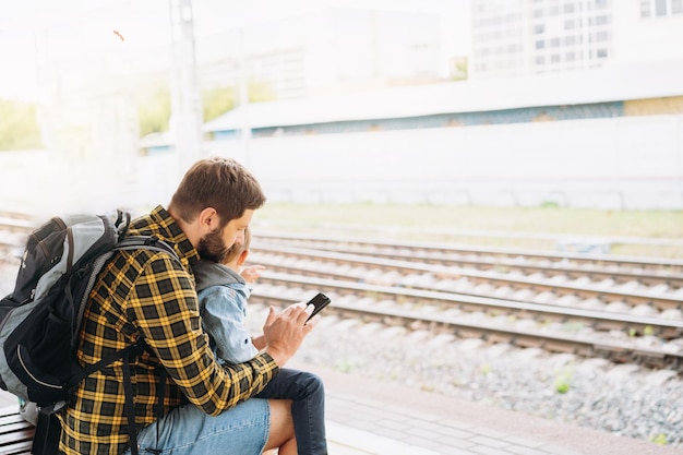 Achteraanzicht van een blanke man die de handen van kinderen vasthoudt en langs het platform loopt om de trein te nemen