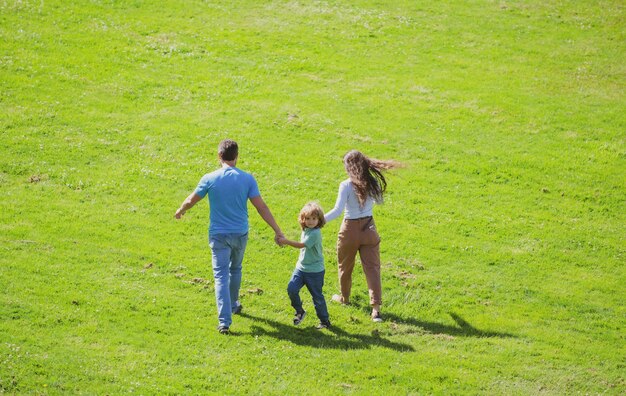 Achteraanzicht van een gelukkig jong gezin dat samen tijd doorbrengt buiten in de groene natuur