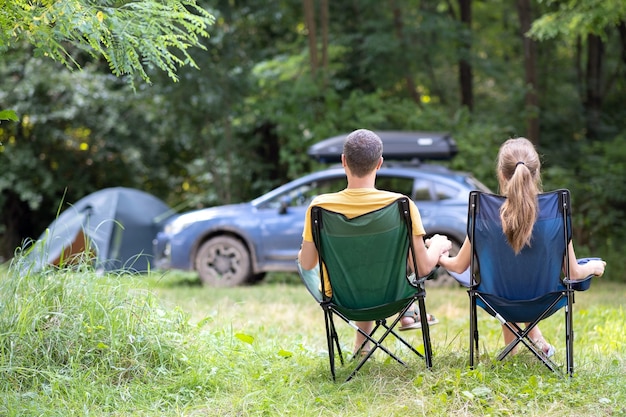 achteraanzicht van een gelukkig paar zittend op stoelen op de camping samen ontspannen.