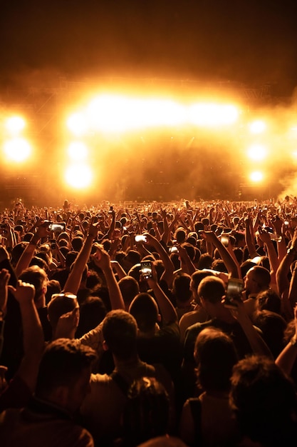 Foto achteraanzicht van een grote groep toeschouwers die 's nachts plezier hebben op het muziekfestival. zo maken ze foto's met smartphones kopieer de ruimte
