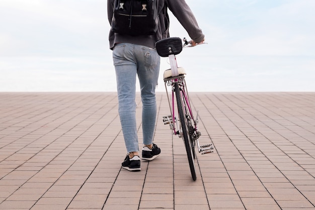 Achteraanzicht van een jonge man die loopt terwijl hij een fietsconcept van ecologisch transport duwt