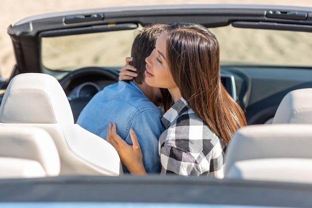 Achteraanzicht van een man die een meisje in een cabrio samen omhelst