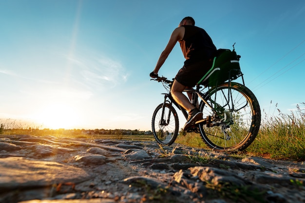 Achteraanzicht van een man met een fiets tegen de blauwe hemel.