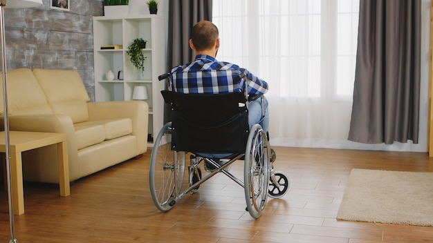 Achteraanzicht van een man met een handicap die op rolstoel zit.