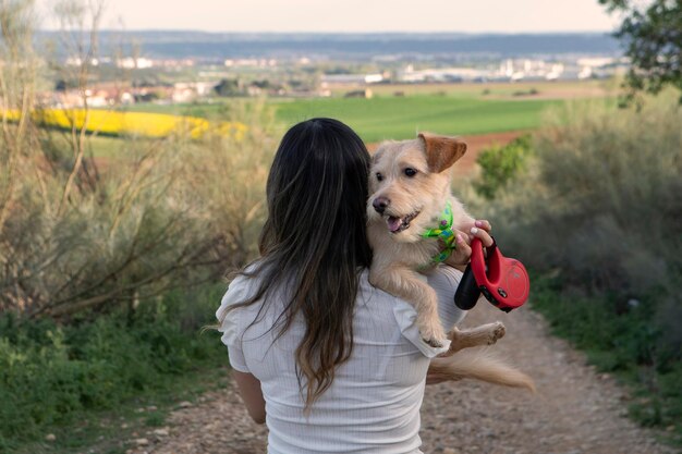 Foto achteraanzicht van een meisje met haar oudere hond in haar armen tijdens haar wandeling