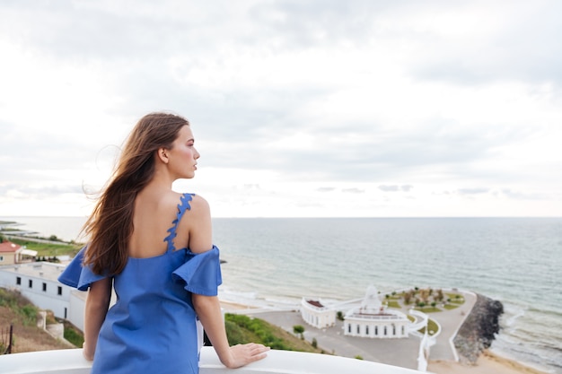 Achteraanzicht van een mooie brunette vrouw stond op het witte terras buiten