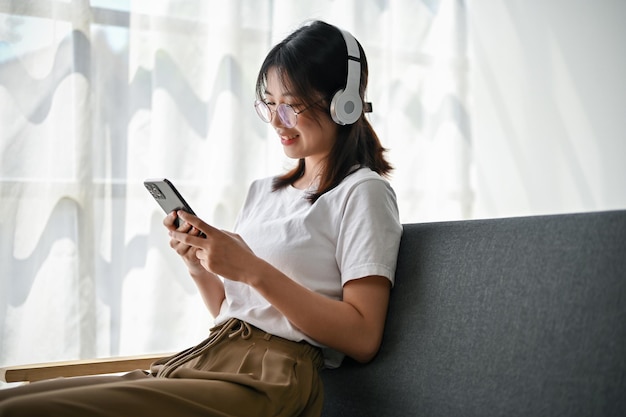 Achteraanzicht van een mooie jonge Aziatische vrouw luistert graag naar muziek op haar telefoon