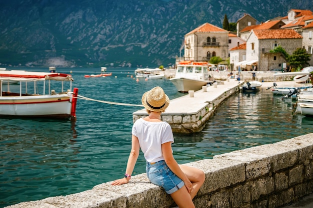 Achteraanzicht van een toeristenvrouw die geniet van het uitzicht op het mooie stadje Perast