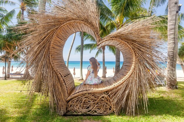 Achteraanzicht van een toeristenvrouw die op een fotoplek zit zoals een strohart met een palmboom