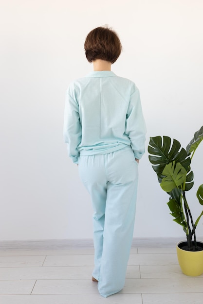 Achteraanzicht van een vrouw gekleed in een prachtige kleurrijke pyjama die zich voordeed als model in haar woonkamer. Comfortabele nachtkleding, thuisontspanning en vrouwelijk modeconcept.