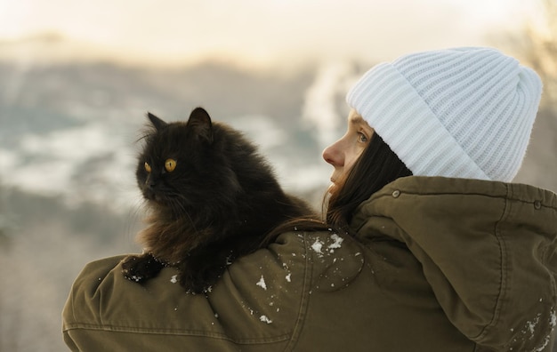 Achteraanzicht van een vrouw in witte hoed met zwarte kat buiten