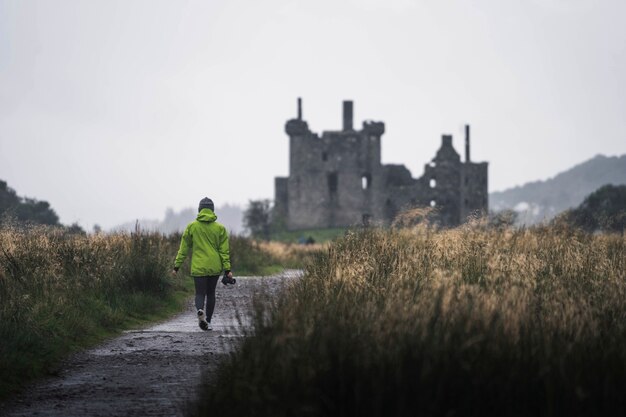 Achteraanzicht van een vrouwelijke fotograaf voor Kilchurn Castle, Schotland