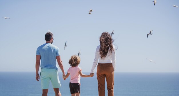 Achteraanzicht van familie op het strand aan de hemel mensen die plezier hebben op zomervakantie vader moeder en kind