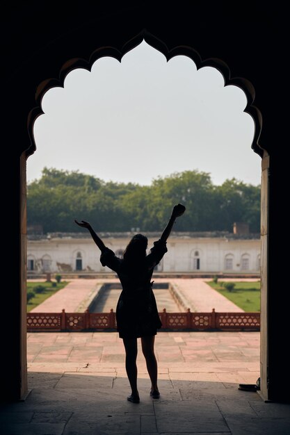 Foto achteraanzicht van het silhouet van de vrouw in jurk met opgeheven handen in het graf van safdar jang in new delhi