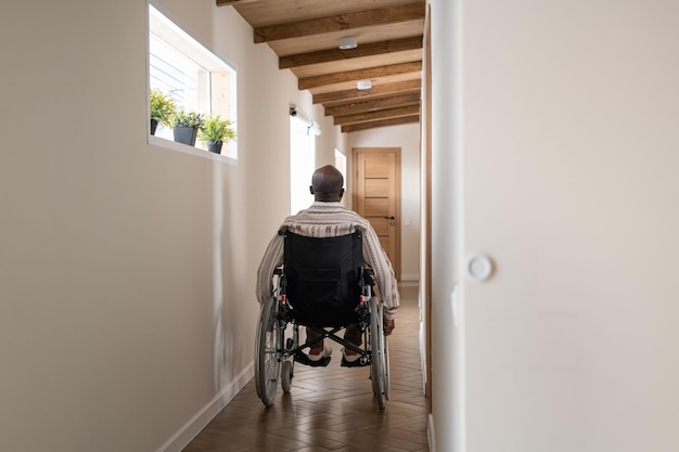 Foto achteraanzicht van jonge afro-amerikaanse man met handicap zittend op rolstoel