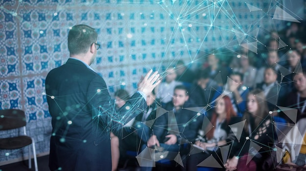 Foto achteraanzicht van jonge succesvolle zakenman in zakelijke vergaderruimte met publiek dat presentaties geeft. publiek in de conferentiezaal. ondernemersclub