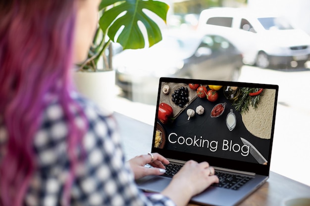 Achteraanzicht van jonge vrouw die blogvideo over gezond eten op laptop bekijkt