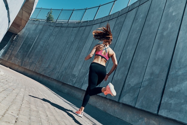 Achteraanzicht van jonge vrouw in sportkleding die buiten loopt