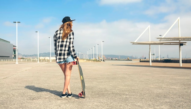 achteraanzicht, van, jonge vrouw, met, longboard, staand, voor, strandpromenade, gedeeltelijk, aanzicht