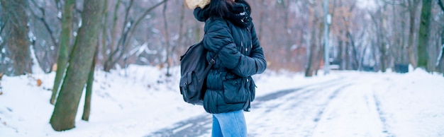 Achteraanzicht van jonge vrouw wandelen in de ongelooflijke winterorest met enorme rugzak